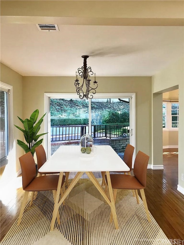 dining space with hardwood / wood-style floors and a notable chandelier