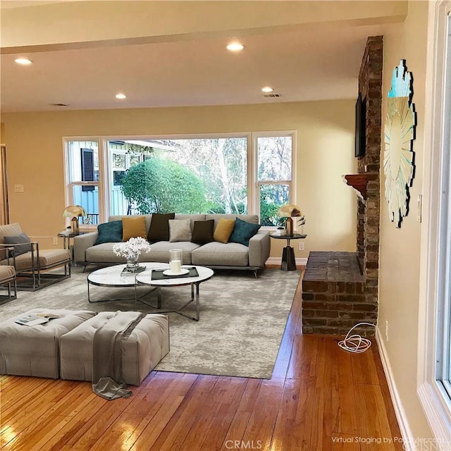 living room with hardwood / wood-style floors and a brick fireplace