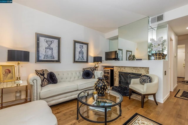 living room featuring a high end fireplace and light wood-type flooring