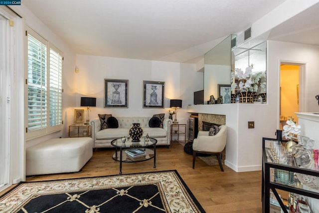 living room featuring a high end fireplace and light hardwood / wood-style flooring