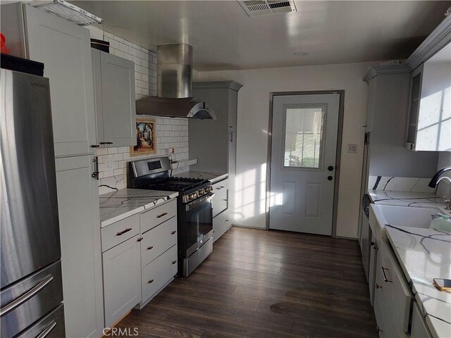 kitchen featuring stainless steel appliances, dark hardwood / wood-style floors, ventilation hood, light stone countertops, and decorative backsplash