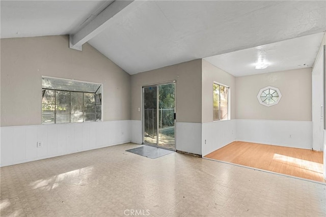 unfurnished room featuring lofted ceiling with beams