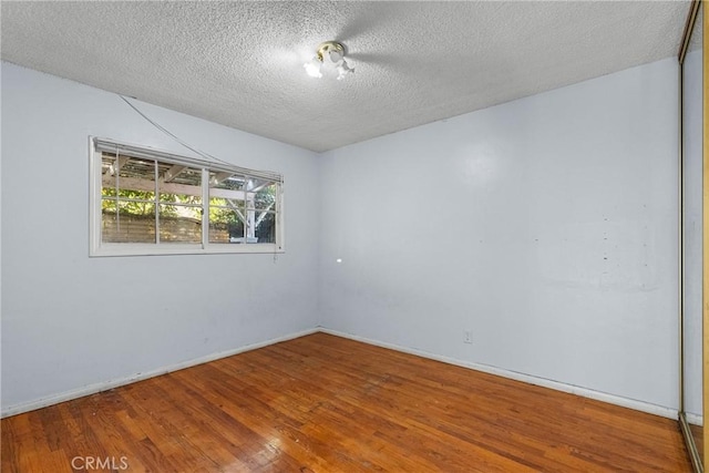 unfurnished room featuring hardwood / wood-style floors and a textured ceiling