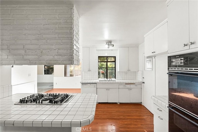 kitchen featuring tasteful backsplash, white cabinets, stainless steel gas stovetop, and tile countertops