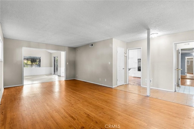 empty room with a textured ceiling and light hardwood / wood-style floors