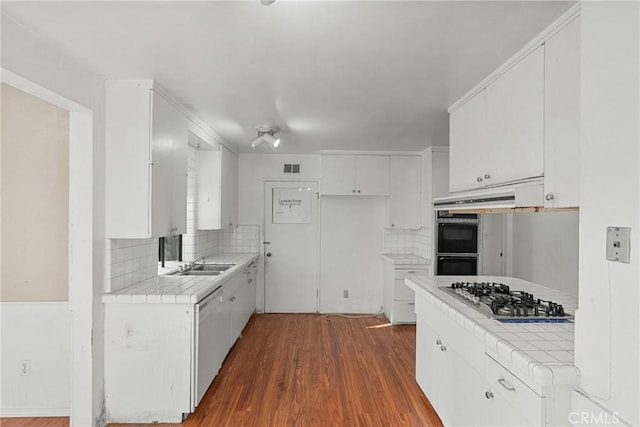 kitchen with tile counters, stainless steel gas cooktop, white cabinets, and dishwasher