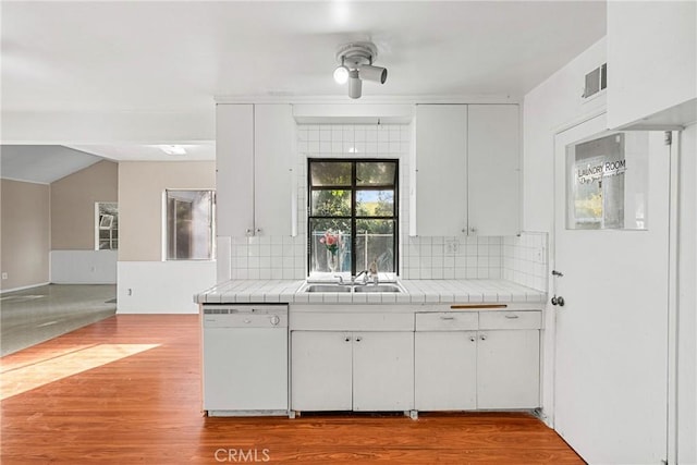 kitchen featuring tile countertops, tasteful backsplash, white dishwasher, white cabinets, and sink