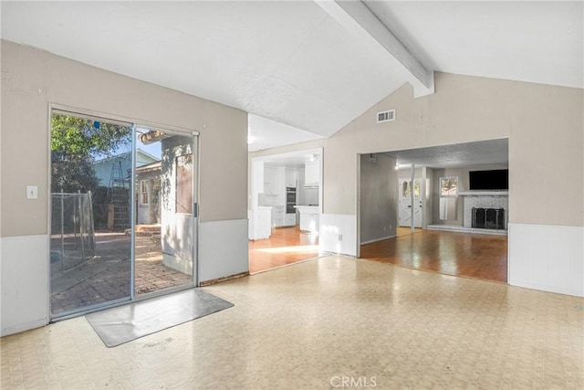 unfurnished living room featuring lofted ceiling with beams and a fireplace