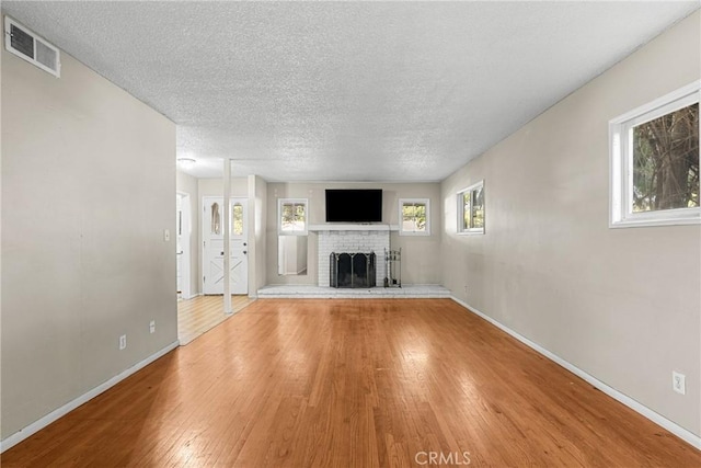 unfurnished living room featuring hardwood / wood-style floors, a textured ceiling, and a fireplace