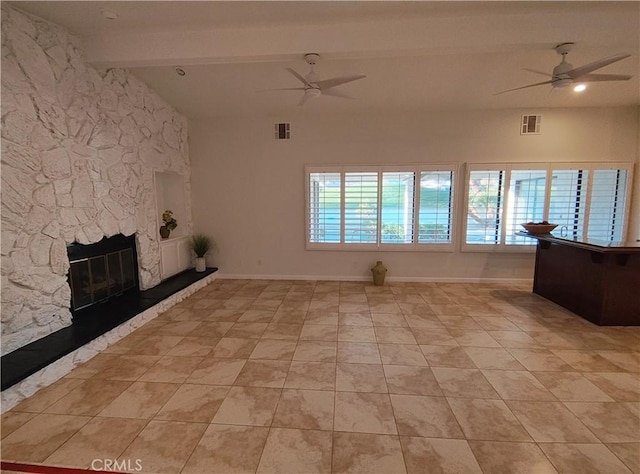 unfurnished living room with ceiling fan, a stone fireplace, beamed ceiling, and light tile patterned flooring