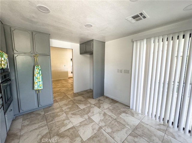 interior space with light tile patterned floors, gray cabinetry, and oven