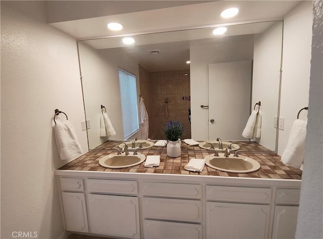 bathroom featuring tiled shower and vanity