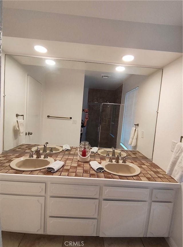 bathroom with walk in shower, vanity, and tile patterned flooring