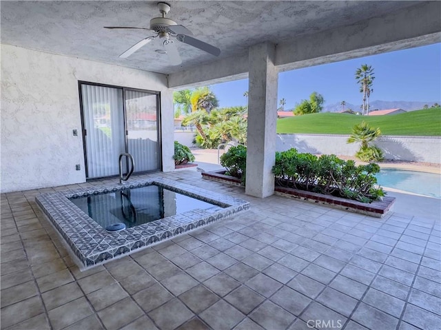 view of swimming pool featuring ceiling fan, a patio area, a mountain view, and a hot tub