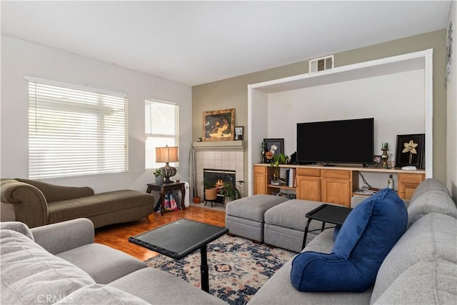 living room with hardwood / wood-style floors and a tiled fireplace