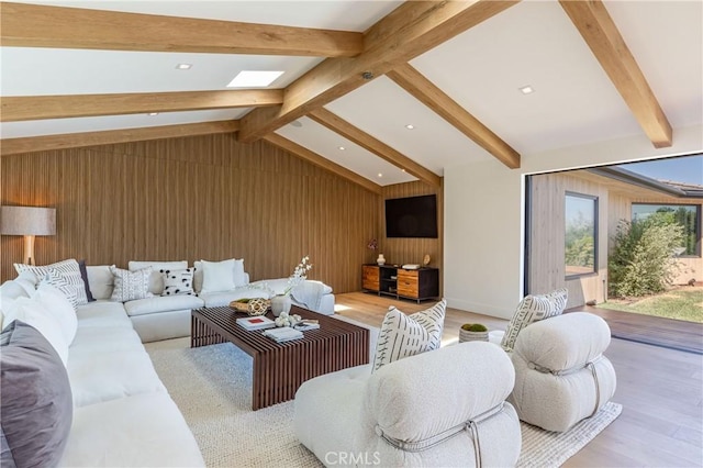 living room featuring light wood-type flooring, wooden walls, and lofted ceiling with skylight