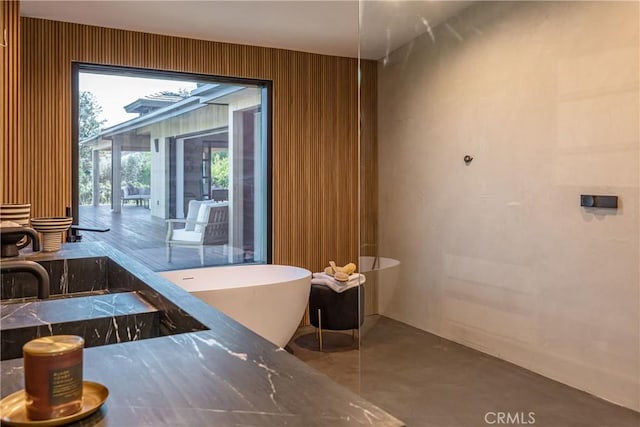 bathroom with a bathing tub, sink, and concrete floors