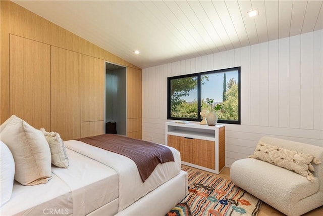 bedroom with wooden walls and vaulted ceiling