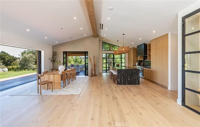 kitchen featuring pendant lighting, a kitchen island, a kitchen bar, and light wood-type flooring