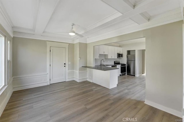 kitchen featuring kitchen peninsula, appliances with stainless steel finishes, sink, light hardwood / wood-style flooring, and white cabinetry