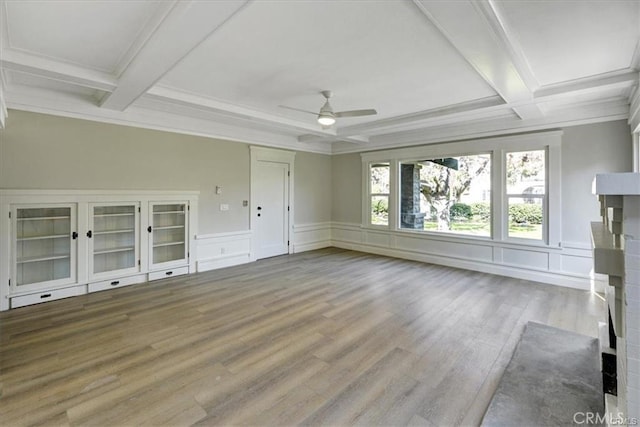 unfurnished living room with beam ceiling, light hardwood / wood-style floors, ceiling fan, and ornamental molding