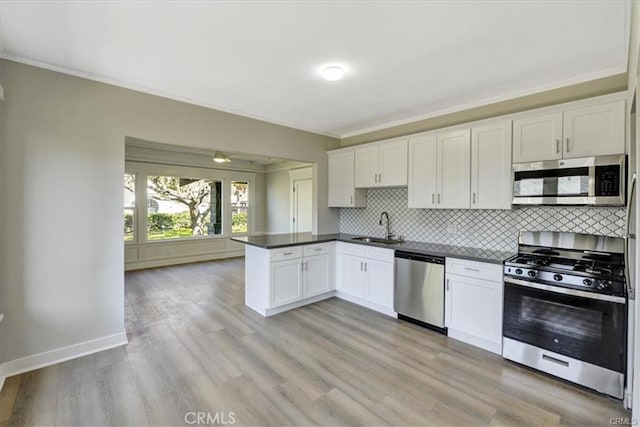 kitchen featuring kitchen peninsula, stainless steel appliances, sink, white cabinets, and light hardwood / wood-style floors