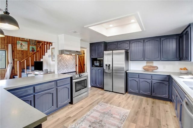 kitchen with pendant lighting, stainless steel appliances, extractor fan, and light hardwood / wood-style floors