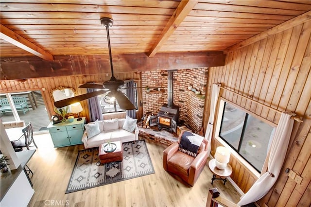 living room featuring a wood stove, hardwood / wood-style floors, and beamed ceiling