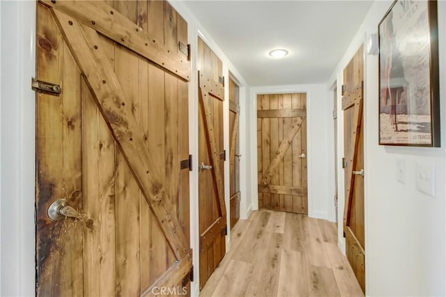 hallway featuring a barn door and light hardwood / wood-style flooring