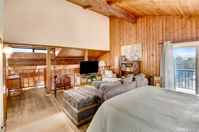 bedroom featuring light wood-type flooring, wooden walls, and multiple windows