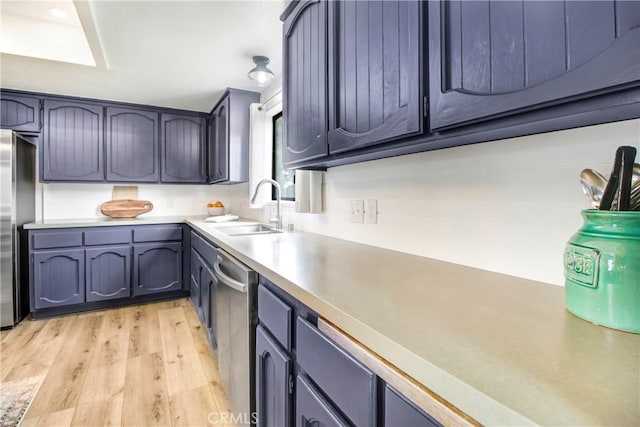 kitchen with blue cabinets, sink, appliances with stainless steel finishes, and light wood-type flooring