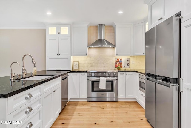 kitchen with white cabinets, wall chimney exhaust hood, stainless steel appliances, and dark stone counters