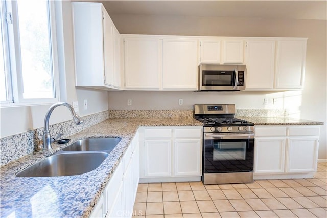 kitchen with white cabinets, sink, light stone countertops, and stainless steel appliances