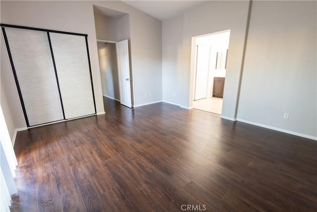 unfurnished bedroom with ensuite bathroom, a closet, and dark hardwood / wood-style floors