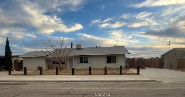 ranch-style home featuring fence and stucco siding