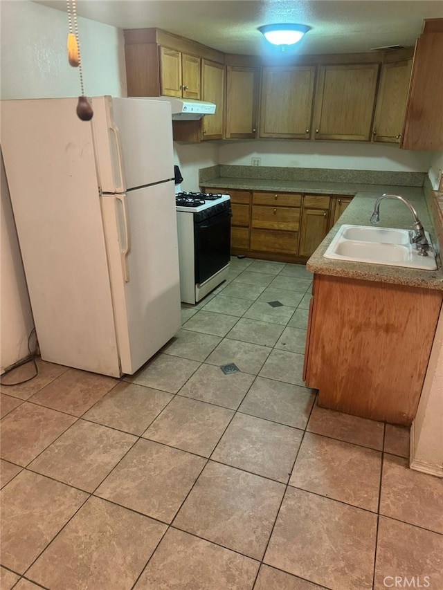 kitchen with white appliances, light tile patterned floors, under cabinet range hood, and a sink