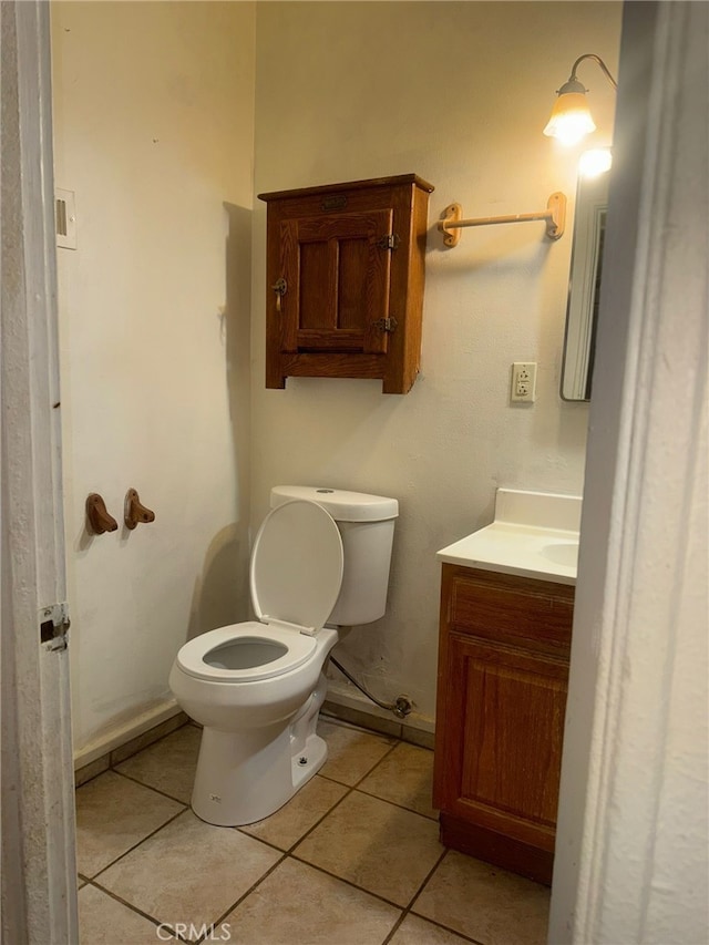 half bathroom featuring tile patterned flooring, baseboards, vanity, and toilet