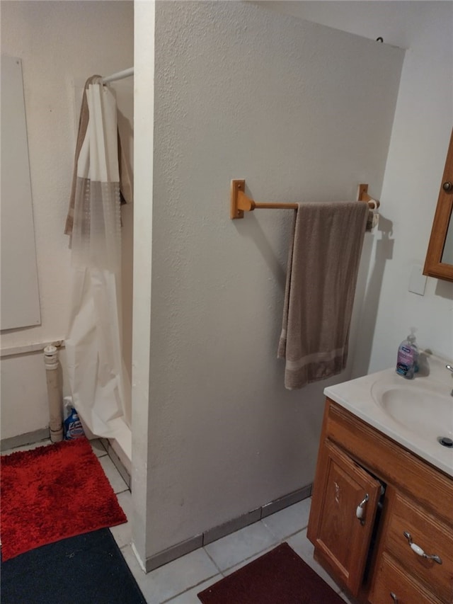 full bath with a stall shower, vanity, and tile patterned floors