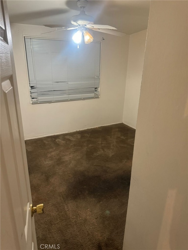 empty room with ceiling fan and dark carpet