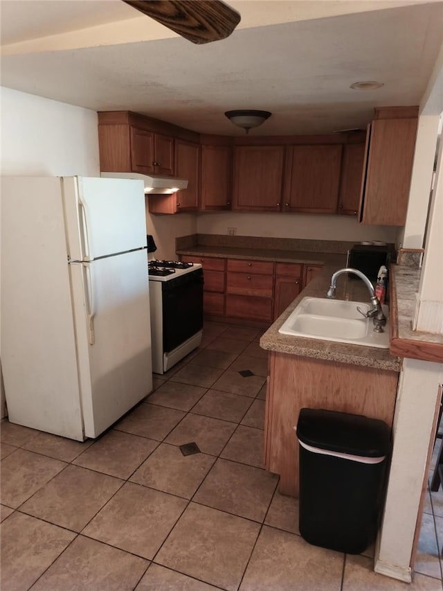 kitchen with white appliances, light tile patterned floors, brown cabinets, under cabinet range hood, and a sink