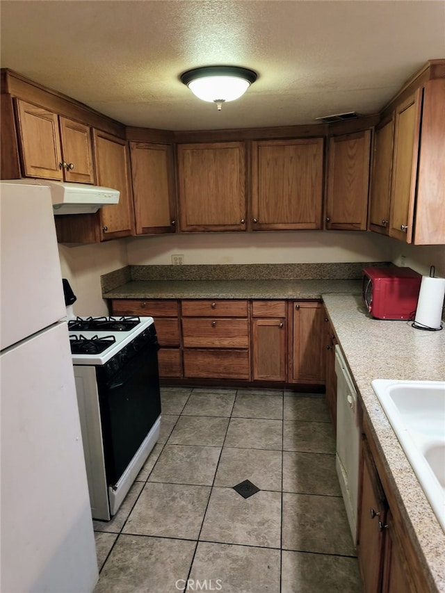 24144 Joshua Ave, Boron, CA 93516 - kitchen featuring white appliances, light tile patterned flooring, under cabinet range hood, brown cabinetry, and a sink