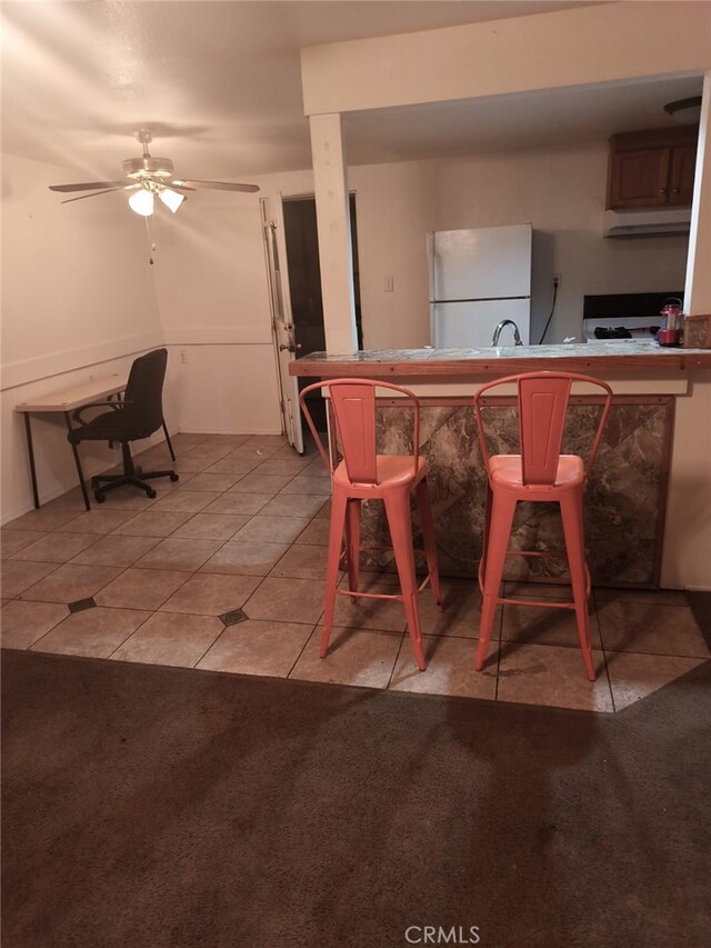 24144 Joshua Ave, Boron, CA 93516 - kitchen with light tile patterned flooring, light colored carpet, freestanding refrigerator, and a ceiling fan