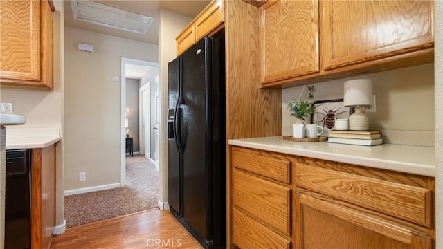 kitchen with light hardwood / wood-style flooring and black fridge with ice dispenser