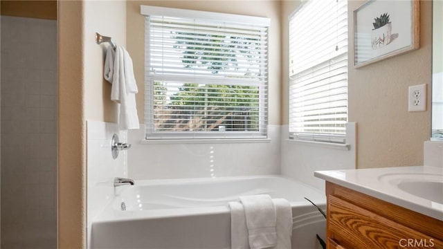 bathroom featuring a wealth of natural light, a bathtub, and vanity