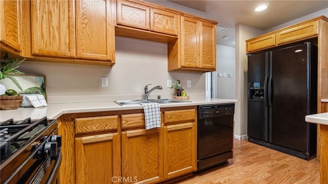 kitchen with black appliances, sink, and light hardwood / wood-style flooring