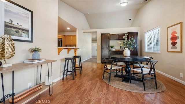 dining area with vaulted ceiling and light hardwood / wood-style floors