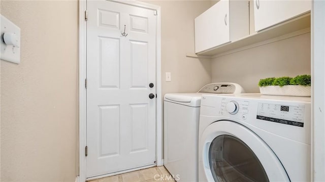 clothes washing area with washer and clothes dryer and cabinets