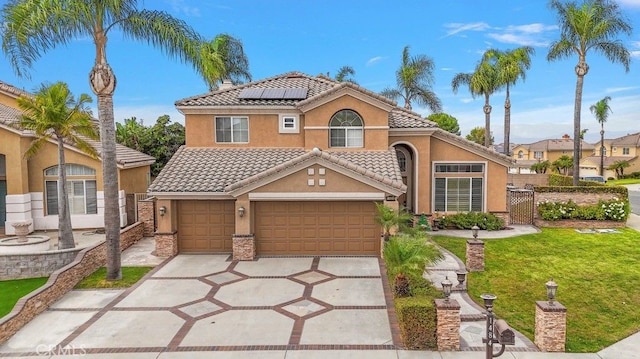 mediterranean / spanish house featuring a garage, a front yard, and solar panels