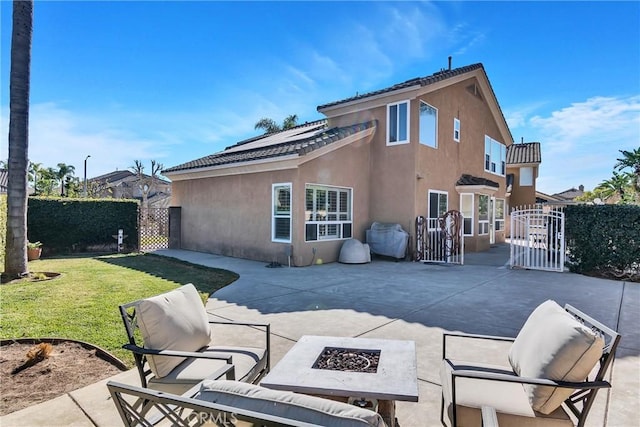 rear view of house featuring a yard, a patio area, and an outdoor fire pit