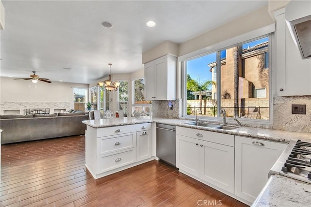 kitchen with pendant lighting, white cabinetry, dishwasher, sink, and kitchen peninsula